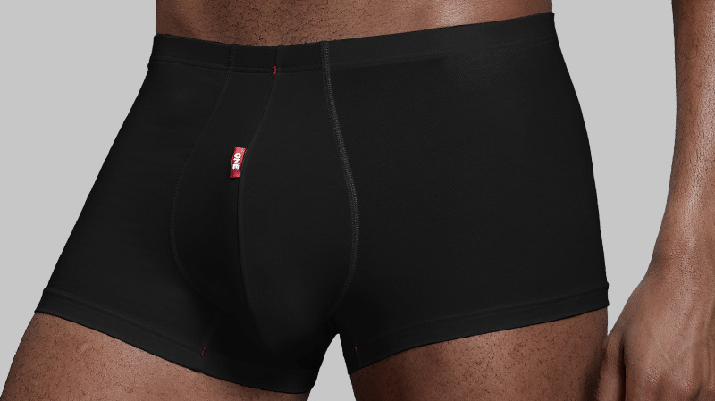 Flat lay of ultralight men's boxer briefs next to a laptop and coffee mug on a modern desk, emphasizing lightweight daily wear