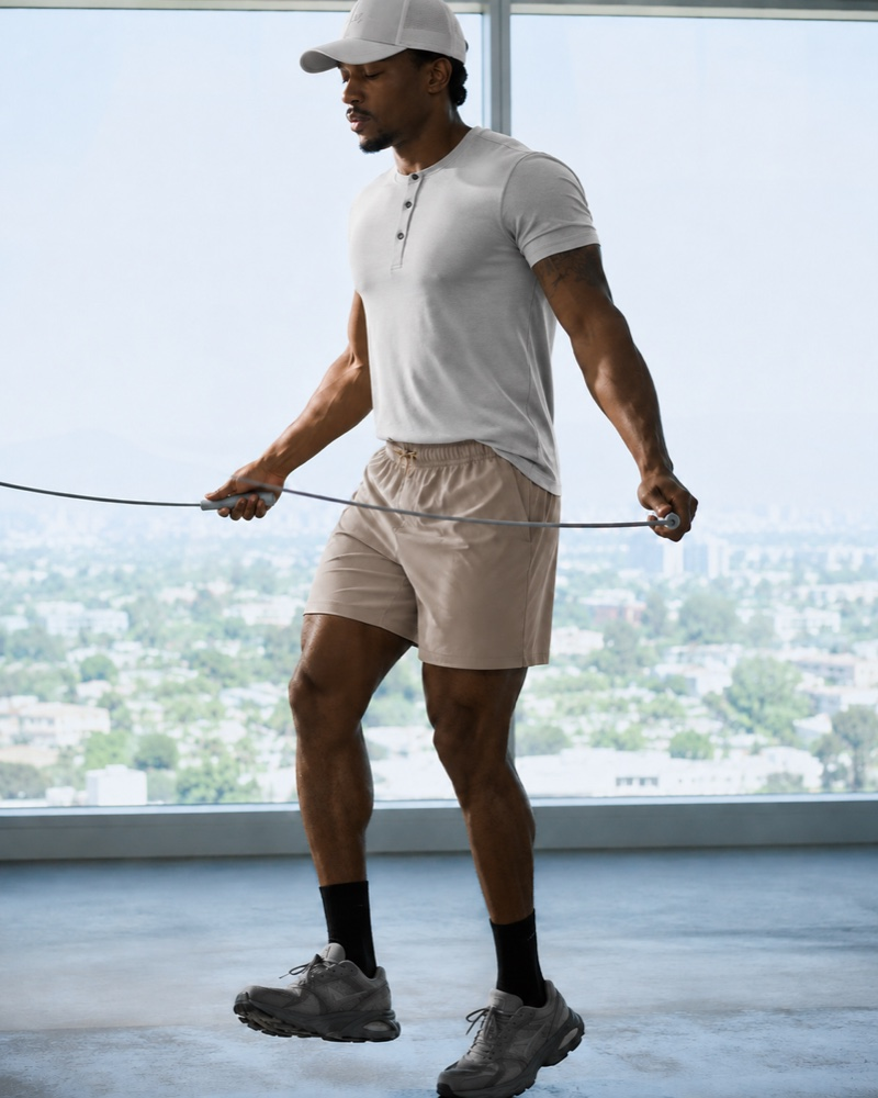 Man in Henley and shorts jumping rope by a city window